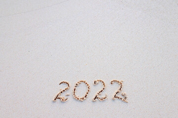 handwritten inscription 2022 on the sand by the sea