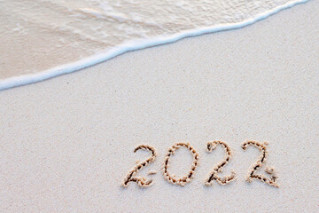handwritten inscription 2022 on the sand by the sea