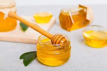 Honey in jar with leaves and honey dipper on colored background top view with copy text