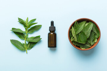 Natural Mint Essential Oil in a Glass Bottle. organic cosmetics with herbal extracts of mint on colored background