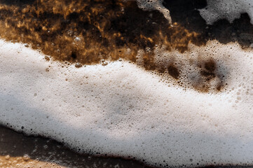 Background, texture of white foam from the sea, ocean on the sand.