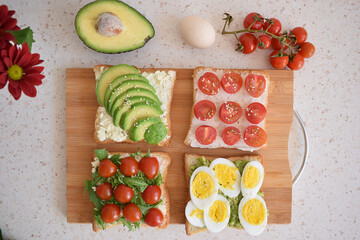 Healthy toast for breakfast with avocado, eggs, tomatoes, arugula etc