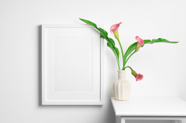 Portrait frame mockup on white wall interior with fresh calla flowers