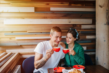 Happy chatting couple sitting in a cafe next to each other, drinking coffee