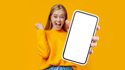 Emotional woman rejoicing success with clenched fist, showing smartphone, mockup