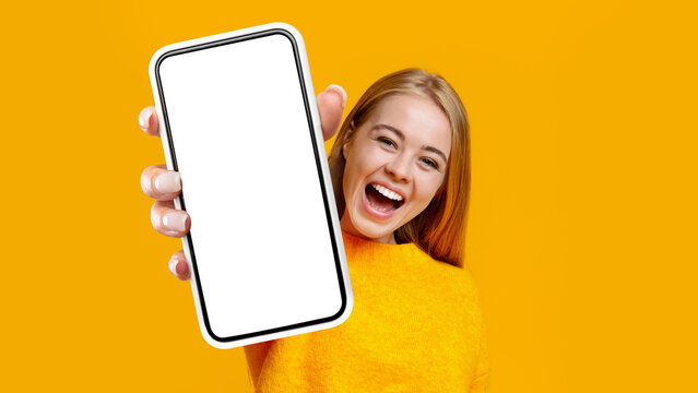 Laughing young woman showing mobile phone, mockup