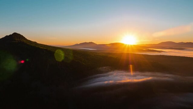 Epic sunrise in mountains. Fog flowing over forest in morning. Mist moving above woods at dawn. Brume floating over hills covered with trees. Amazing landscape with steam. Timelapse shot