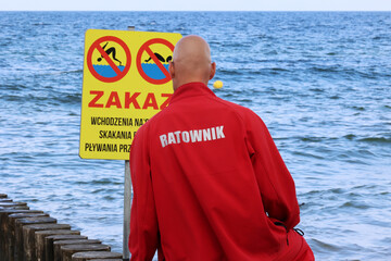 Ratownik na plaży podczas patrolowania brzegu wody nad morzem latem. 