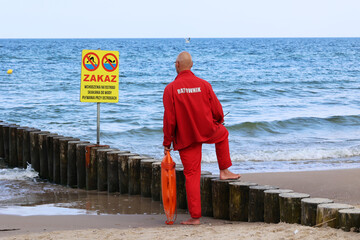 Ratownik na plaży podczas patrolowania brzegu wody nad morzem latem. 
