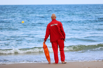 Ratownik na plaży podczas patrolowania brzegu wody nad morzem latem.  - obrazy, fototapety, plakaty