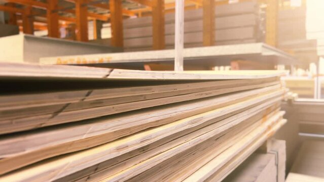 Stacks of sheet plywood lie in a warehouse of a woodworking factory. Close-up shot