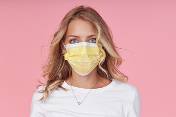 A young attractive woman in a white casual t-shirt wears a protective face mask. Protection against...