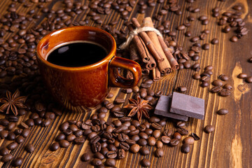 ceramic brown cup with black coffee and grains on wooden background still life