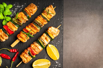 .Chicken shish kebab with zucchini. Top view.Grilled pieces of chicken meat on skewers.Grilled chicken kebab with vegetables on a black background