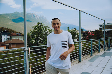 A man against the backdrop of mountains and flowers on a sunny day tourist smiles and rests in Italy. hipster photo.