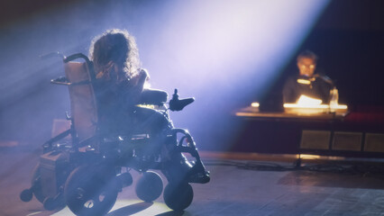 A woman with spinal muscular atrophy having an audition on a theater stage illuminated by a...