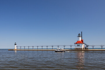 Fototapeta na wymiar Boat in the channel and St. Joseph North Pier Inner Lighthouse and St. Joseph North Pierhead Outer Lighthouse, Michigan 