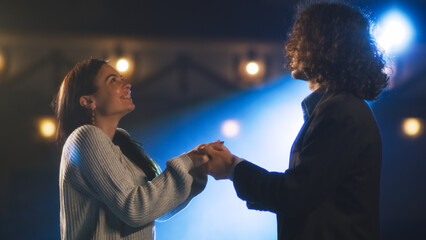 Male and female theater actors holding hands during a rehearsal of a romantic play on a stage...