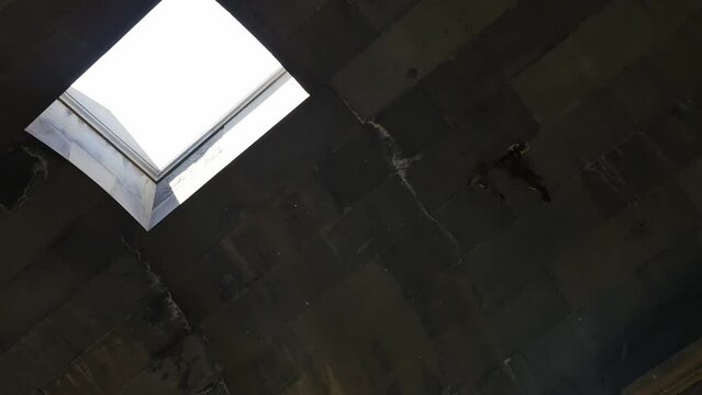 In the roof of the ancient temple there is a hatch through which the sun's rays shine and particles and dust particles are visible in the sunlight.