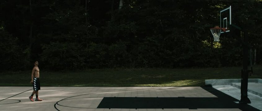 Teen shoots a 3 pointer on a basketball court in slo-mo (Cinemascope)