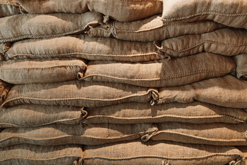 large burlap canvas bags of coffee beans stacked up in a local coffee shop or manufacturer or store