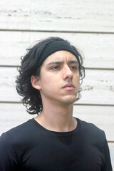 Young man pensively looks up with a white wall behind him