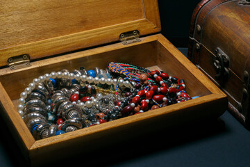 old wooden chest containing cheap jewelry on dark background