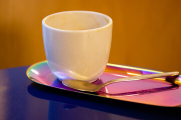 White ceramic cup without handle for cappuccino latte tea stands on stylish pink tray on blue...
