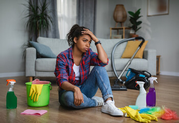 Frustrated tired unhappy young black woman housewife suffering from a lot of housework sit on floor