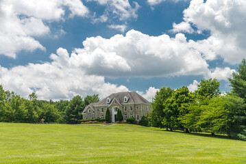 View of a rich country house for a large family with a lawn and a cloudy sky.