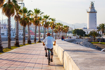 Fototapeta na wymiar Walkway along the sea close to Malagueta beach, Andalusia, Spain. Old man on the bicycle in Malaga