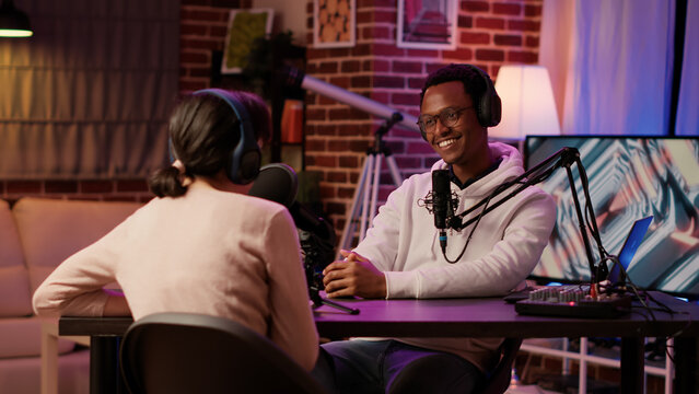 African american podcaster introducing famous influencer to listeners in evening online show from home studio. Diverse content creators talking in internet radio live interview recording podcast.
