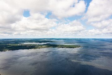 Waubaushene beach shoreline with clouds green treetops and blue skys