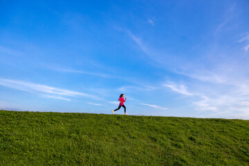 Fototapeta premium Young Asian girls jogging for fitness in the open grass