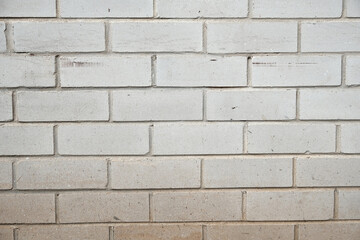Brick wall made from white bricks and white mortar cement. Wall is illuminated strong sidelight showing strong relief in the space between bricks and all the surface wear, scratches and weathering