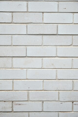 A brick wall made from white bricks with white mortar, showing surface wear and scuffs