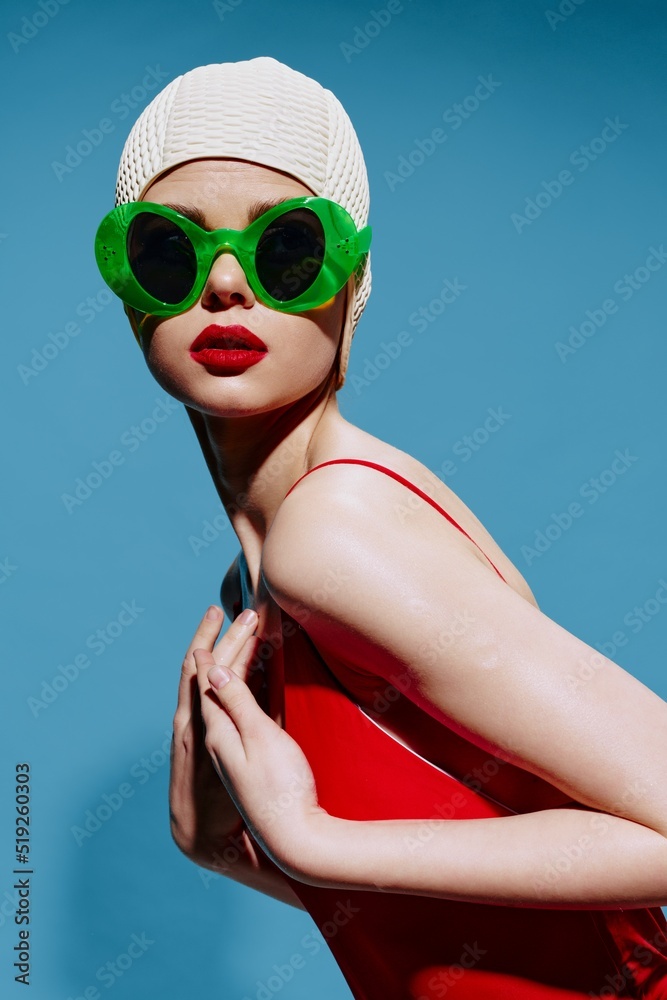 Sticker an unusual woman in a swimming cap and a red swimsuit bends in the studio on a blue background. art 