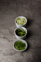 green chili, spring onion and pickle on white bowl and texture background