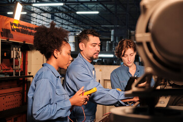 Multiracial professional industry engineer teams in safety uniforms work by inspecting machines' voltage current, checking, and maintaining at manufacture factory, electric system service occupations.