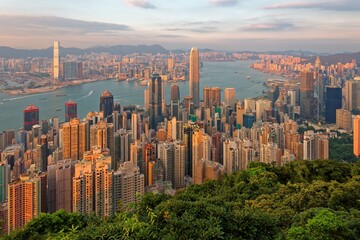 Sunset scenery of Hong Kong viewed from top of Victoria Peak, with city skyline of crowded skyscrapers by the harbour & Kowloon area across seaport ~ Beautiful cityscape of Hongkong in golden sunlight