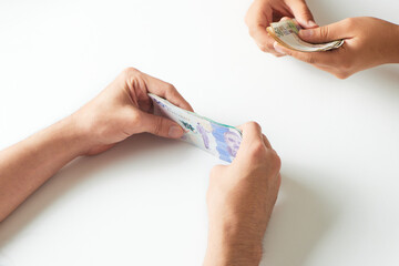 Hands receiving Colombian money from another person on a white background