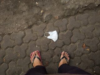 Abandoned face mask on the floor. It made from fiber or gauze and fitting over the nose and mouth to protect against dust or air pollutants.