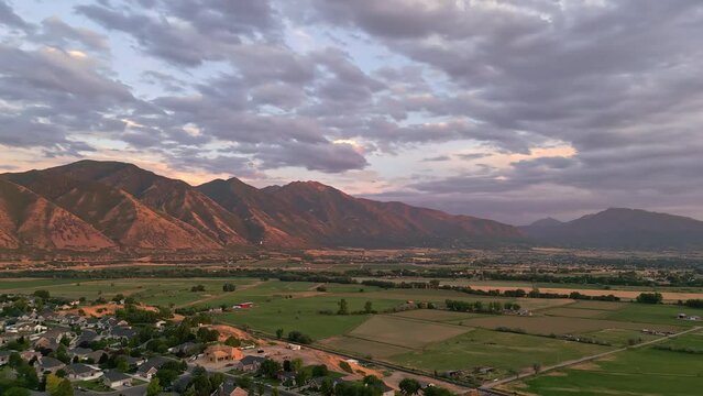 Rotating aerial view wear farmland and city meets in Spanish Fork, Utah during sunset.