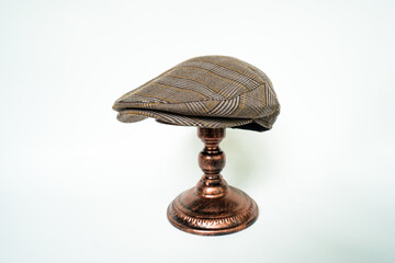Detail of scally or flat cap in dark brown pattern  herringbone tweed fabric set on a bronze head...