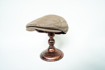 Detail of scally or flat cap in dark brown pattern  herringbone tweed fabric set on a bronze head...