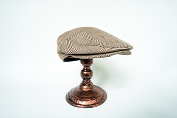Detail of scally or flat cap in dark brown pattern  herringbone tweed fabric set on a bronze head...