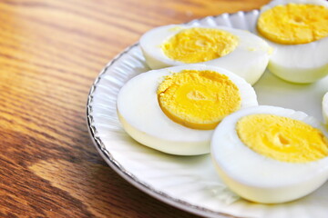 Half boiled eggs laid out in white plates and served on a wooden table.