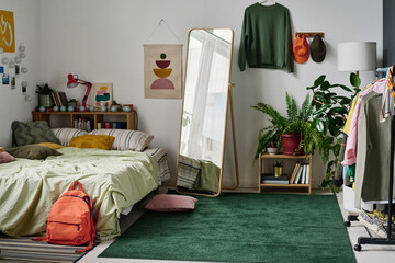 Stylish teenage room interior with comfortable bed and with clothing and mirror in the centre
