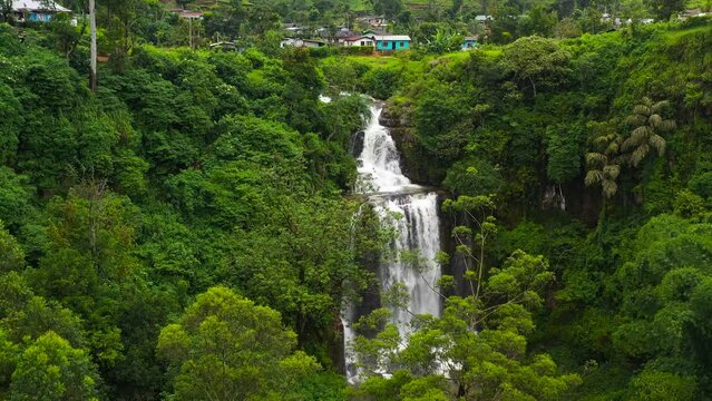Aerial view of waterfall in a mountainous province among hills with tea estate. Mount Vernon, Sri Lanka.