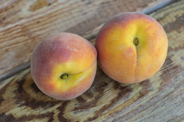 Two fresh peaches on wooden background close up